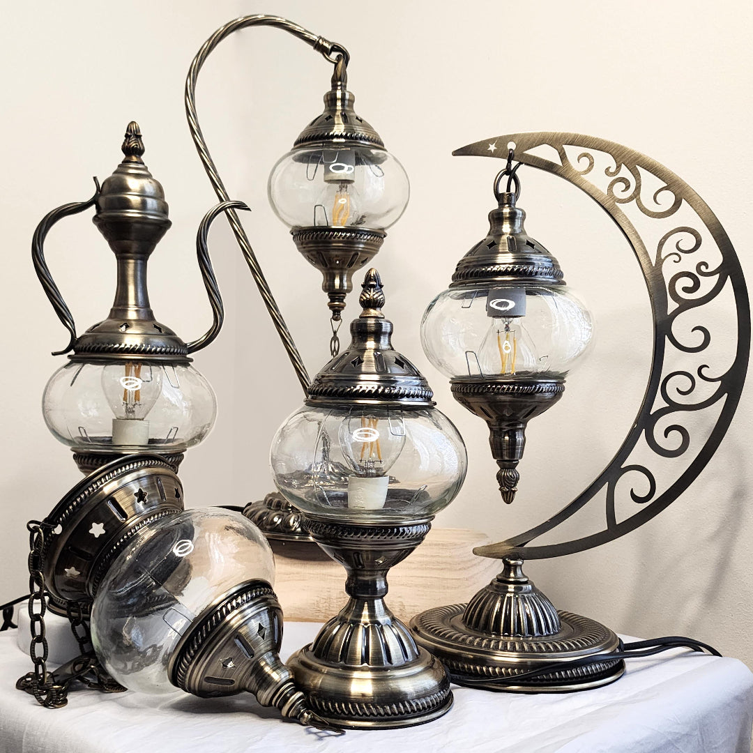 Turkish-style lamps with glass globes and metallic finishes on a white surface.