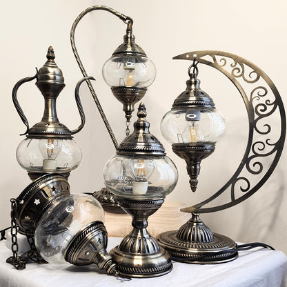 Turkish-style lamps with glass globes and metallic finishes on a white surface.